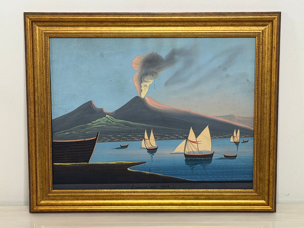 A framed antique coastal marine painting depicting an erupting volcano over a blue sea with several sailboats, housed in an ornate gold frame.